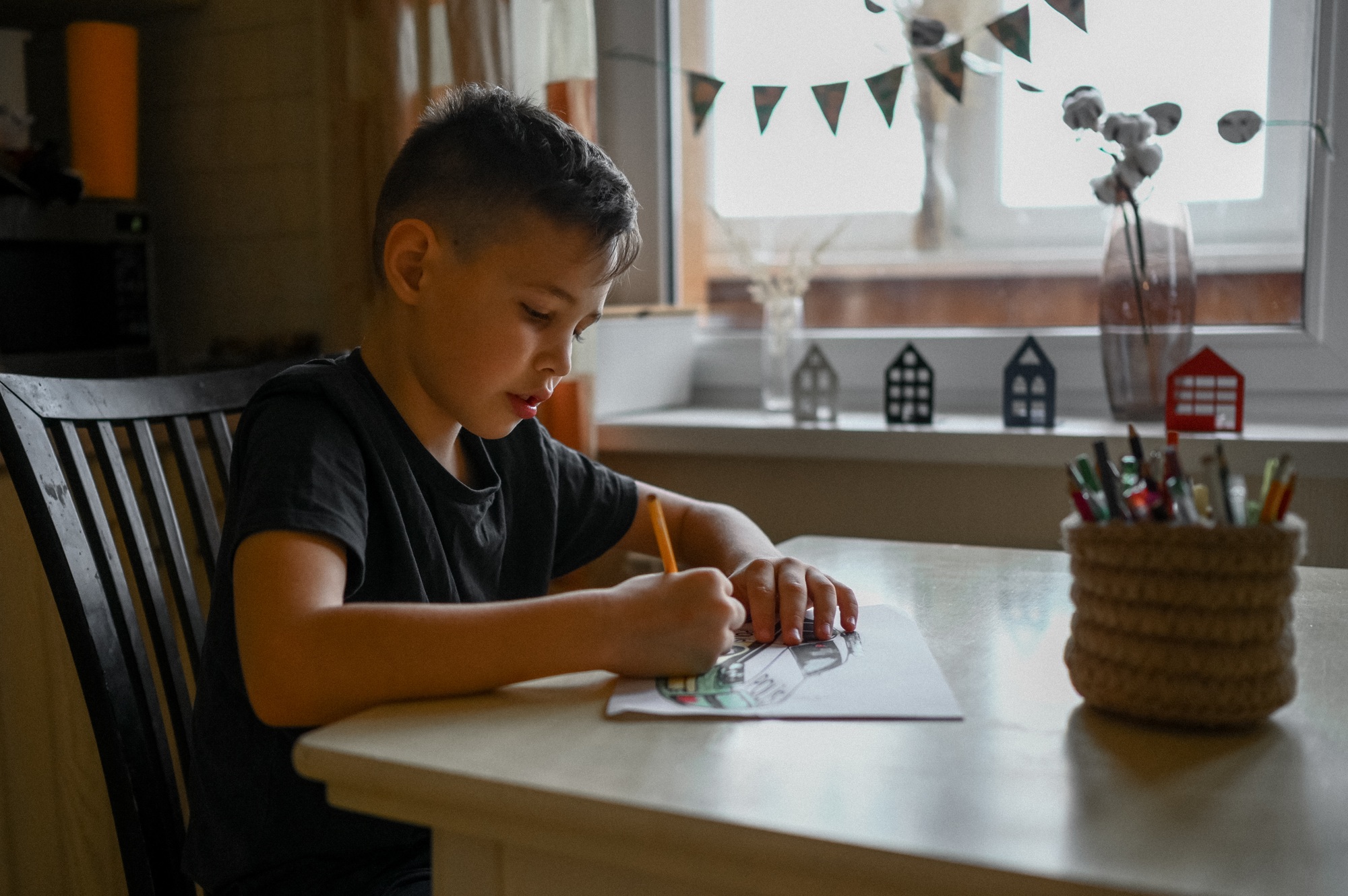 A 10-year-old boy draws a drawing with colored pencils