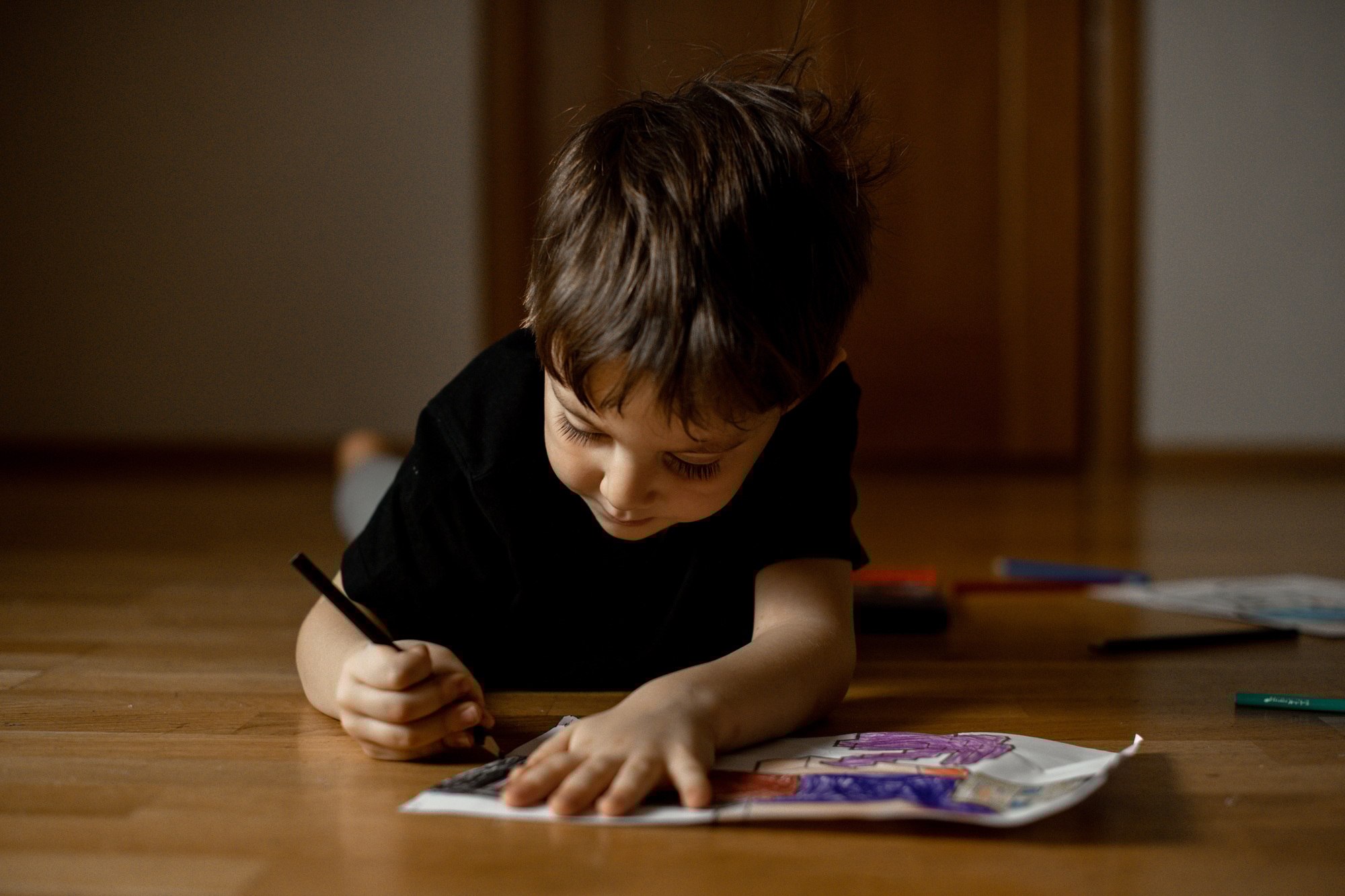 A little boy 5 years old draws a drawing with colored pencils
