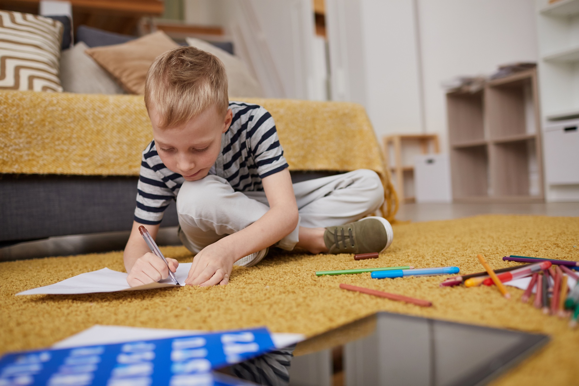 Boy drawing on paper in living room