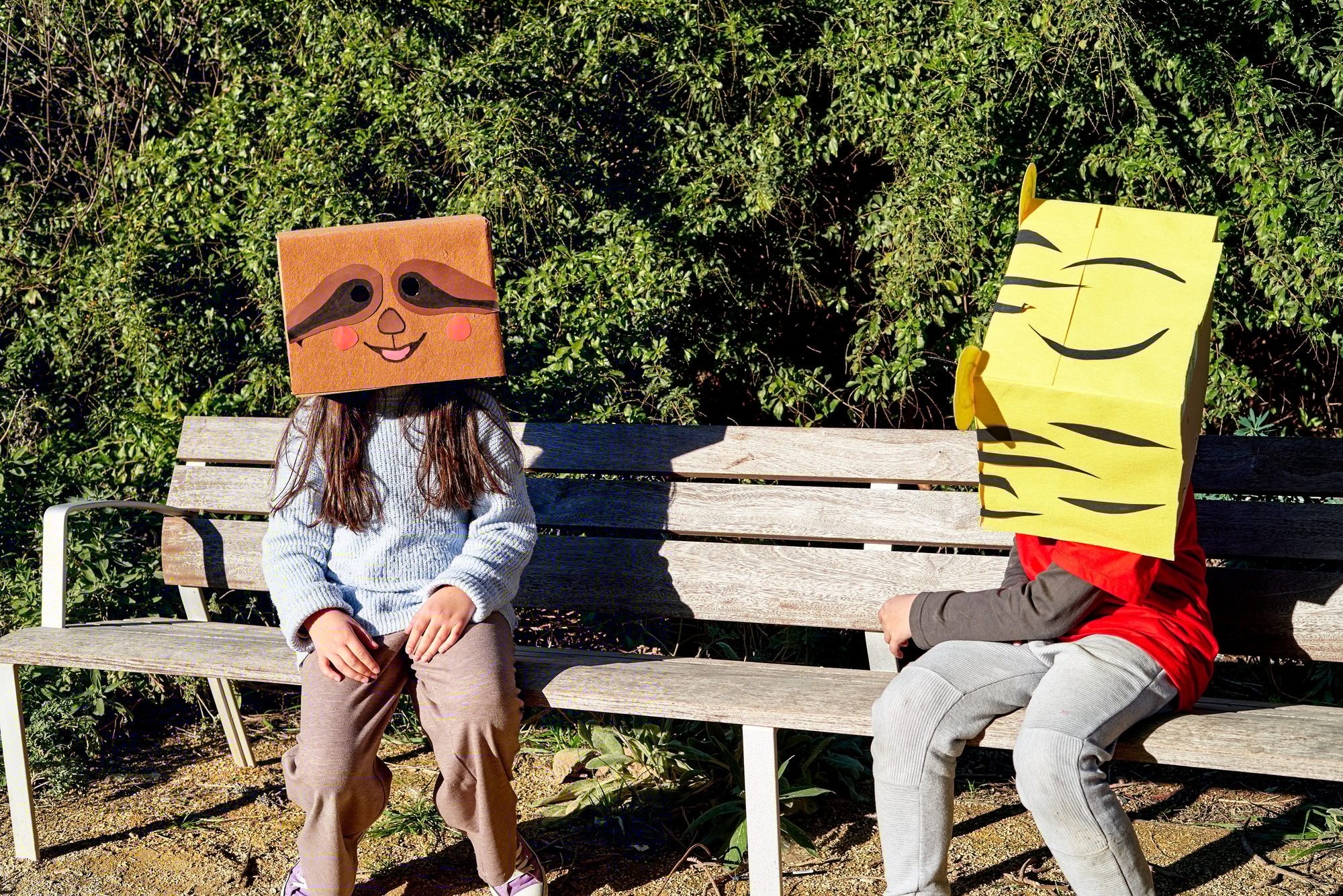 Children with heads in a cardboard box, decorated it to look like animals