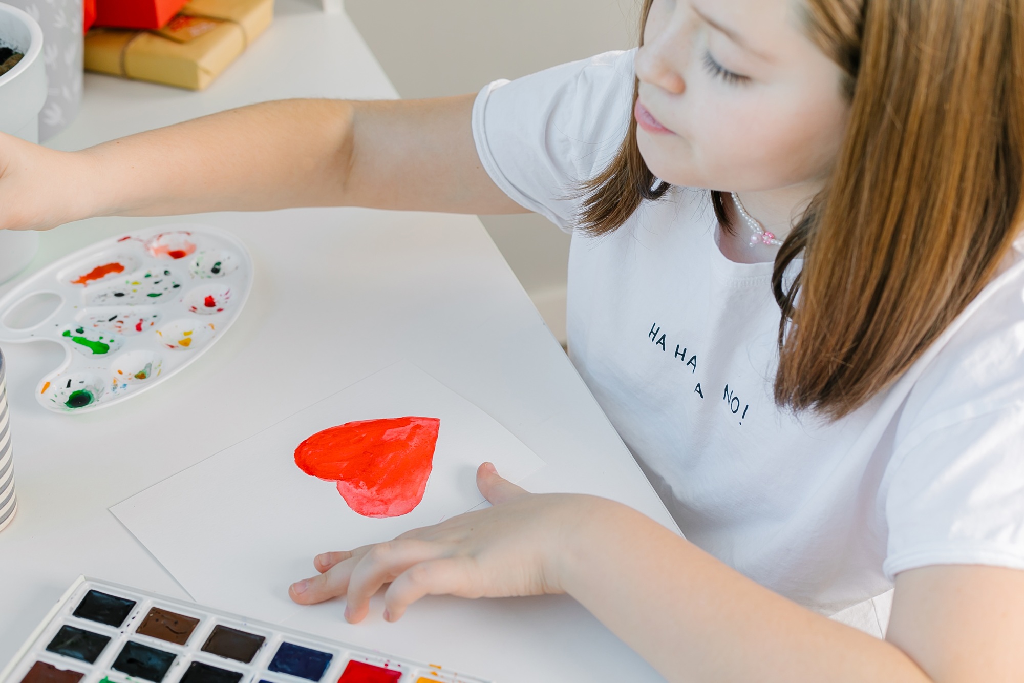 Girl drawing red heart on with watercolors