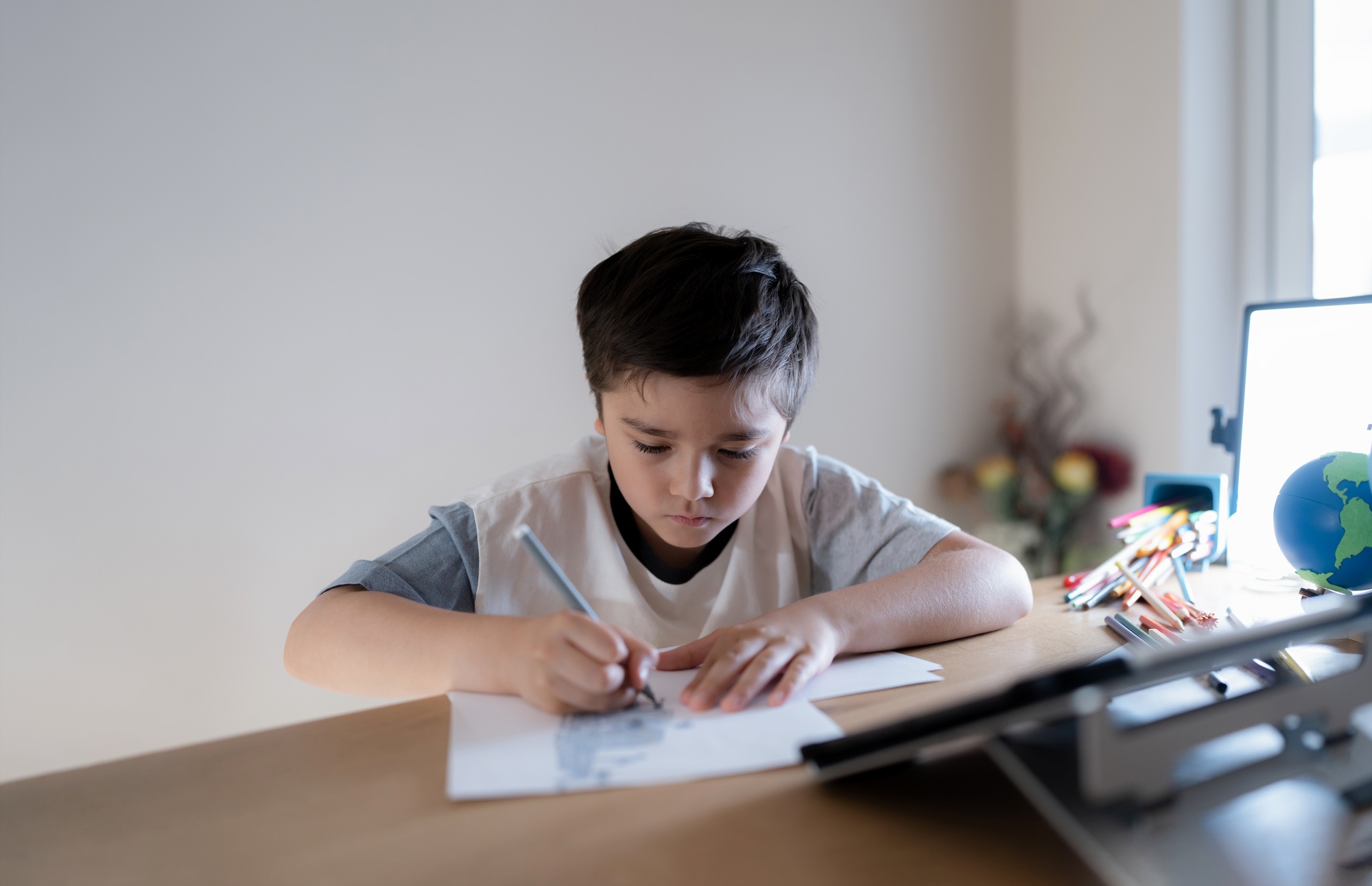 School kid using grey colour pen drawing or sketching on paper,Portrait boy doing homework