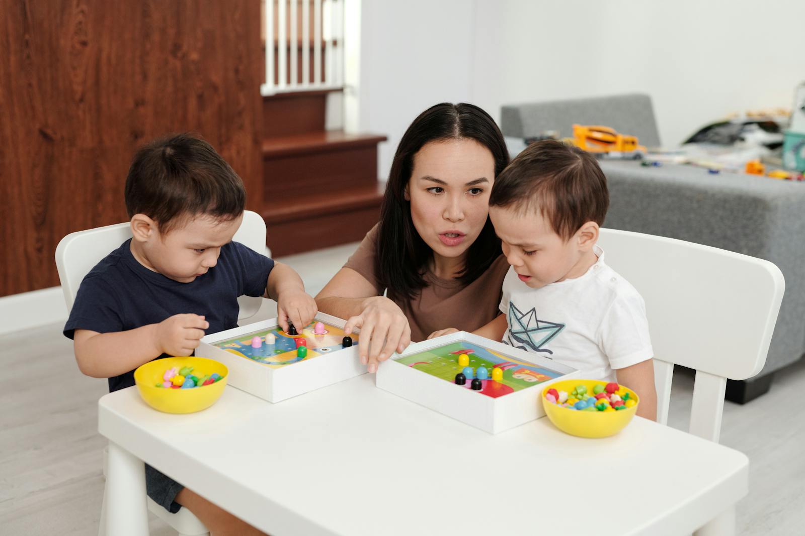 A mother guides her two young children during creative playtime at home.
